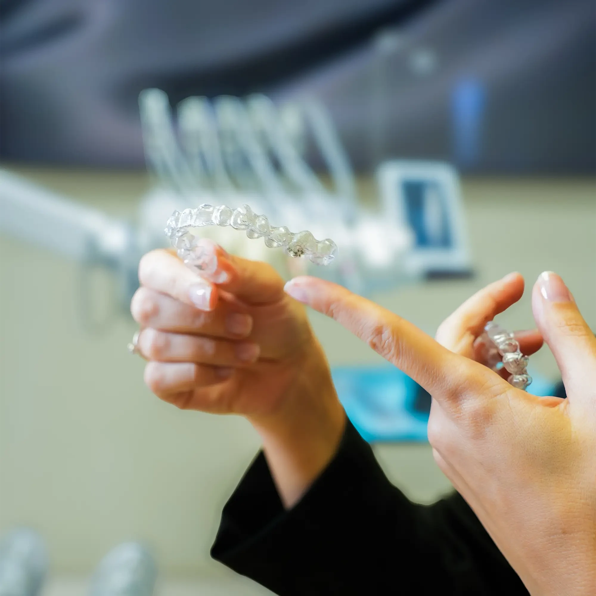 A dentist is holding Invisalign aligners
