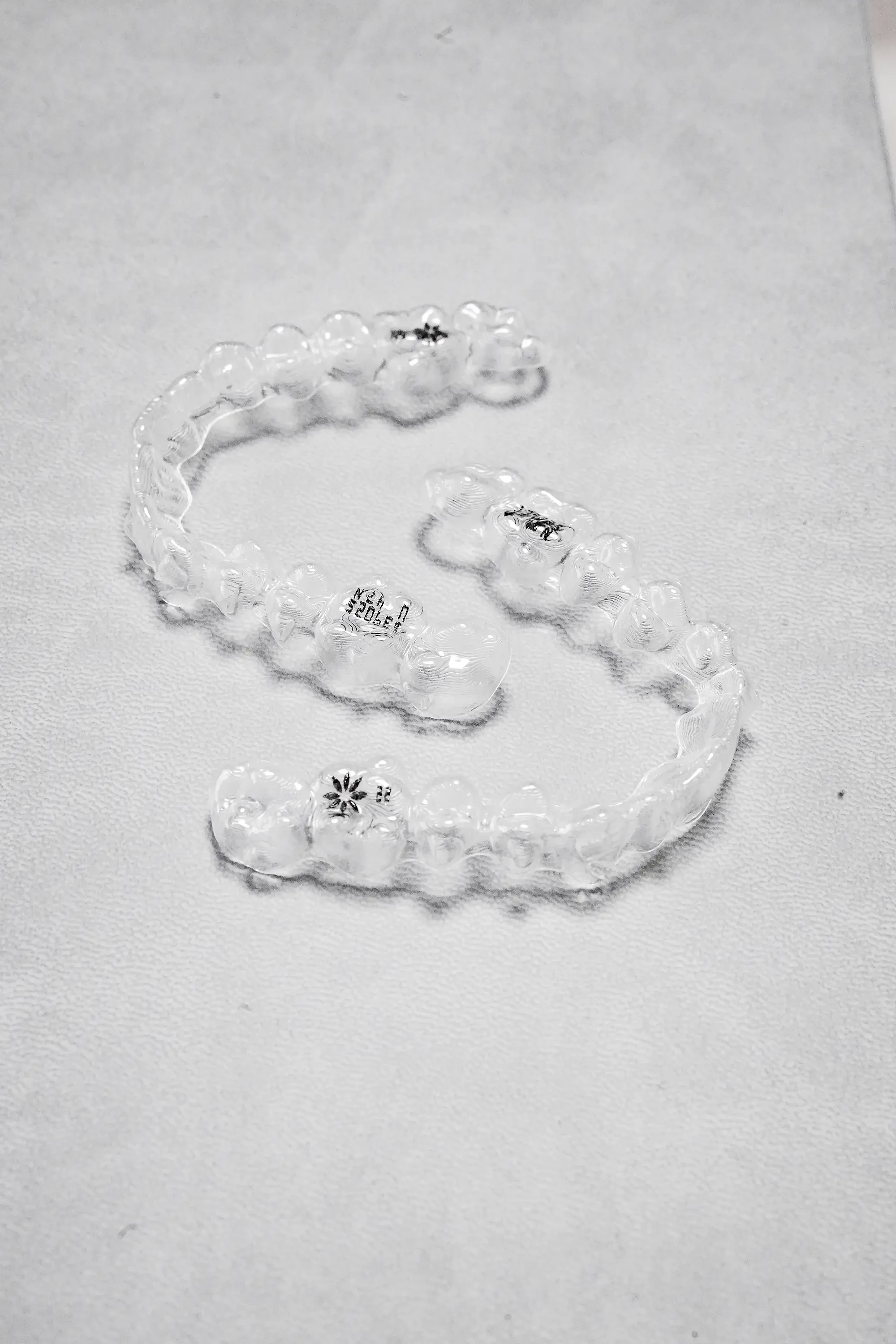 A pair of Dr. Nana’s specially designed aligners lie against a uniform light-colored background